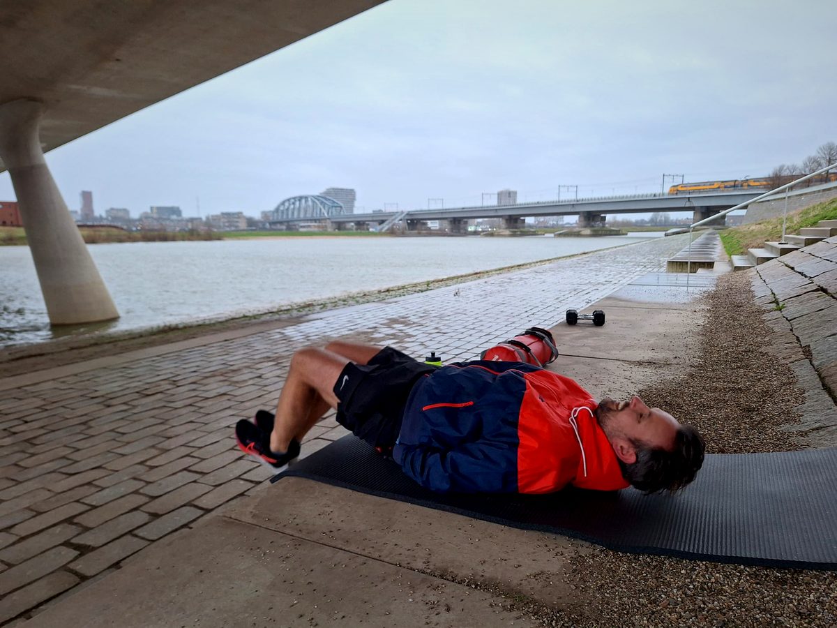 Iemand doet een buikspieroefening op een mat aan het water