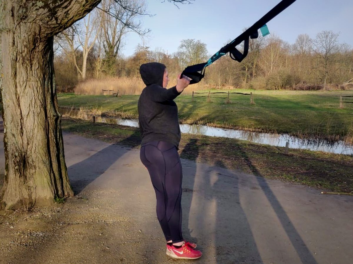 Iemand trekt zich op aan een ophangsysteem dat aan een boom hangt